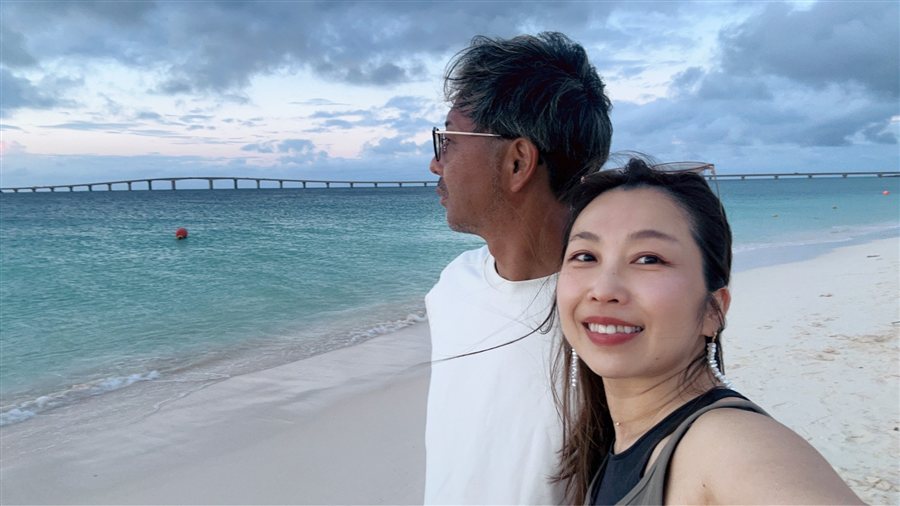 海辺で夫と並ぶ花本加奈