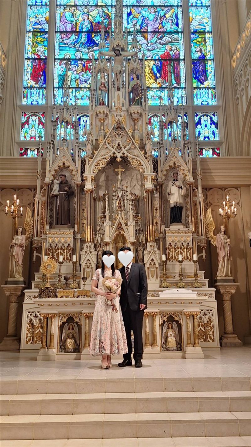 大聖堂の祭壇の前に並ぶお二人（お顔はハートで隠しています）